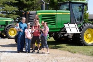 Family smiling in front of tractor